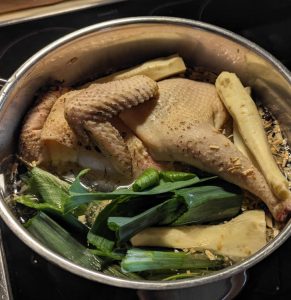 Suppenhuhn und Suppengemüse im Kochtopf