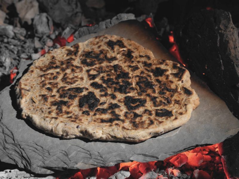 Fladenbrot auf einer Steinplatte in der Lagerfeuerglut