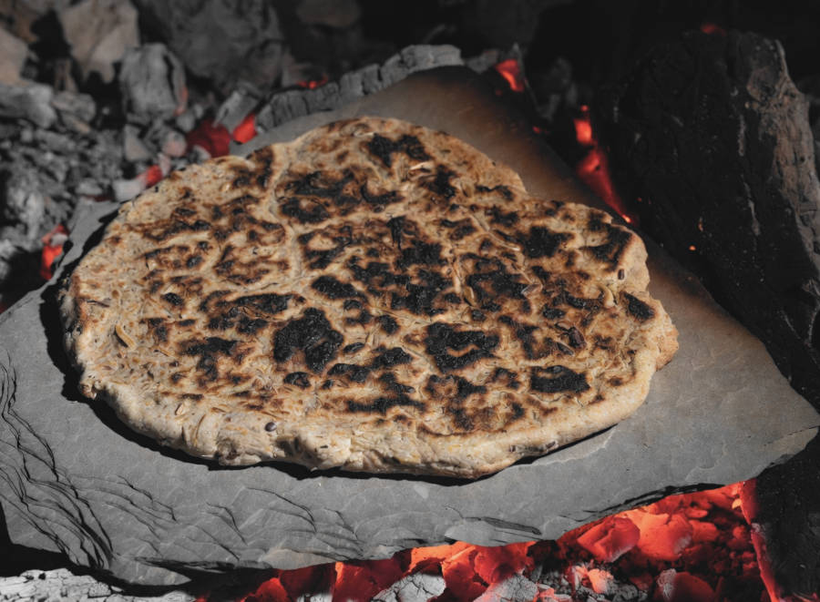 Fladenbrot auf einer Steinplatte in der Lagerfeuerglut
