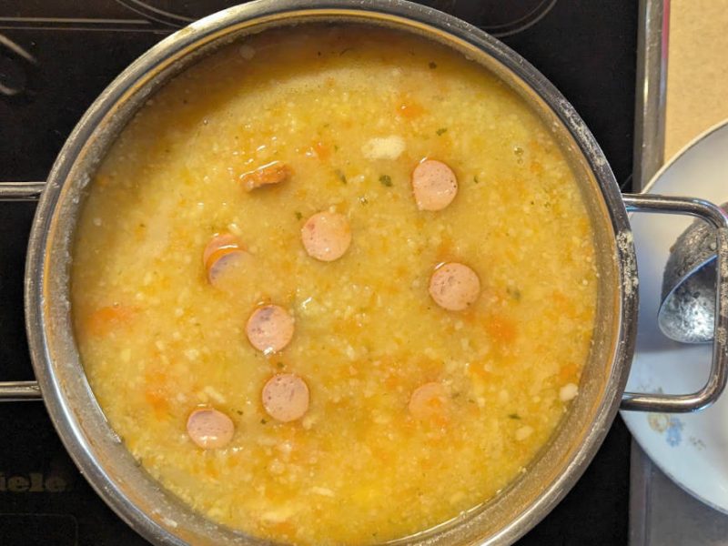 Kartoffelsuppe mit Wurstscheibchen in einem Kochtopf