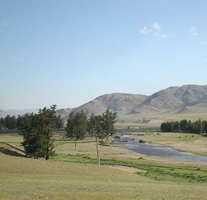 Hügelige Steppenlandschaft mit Fluss und kleinen Wälchen